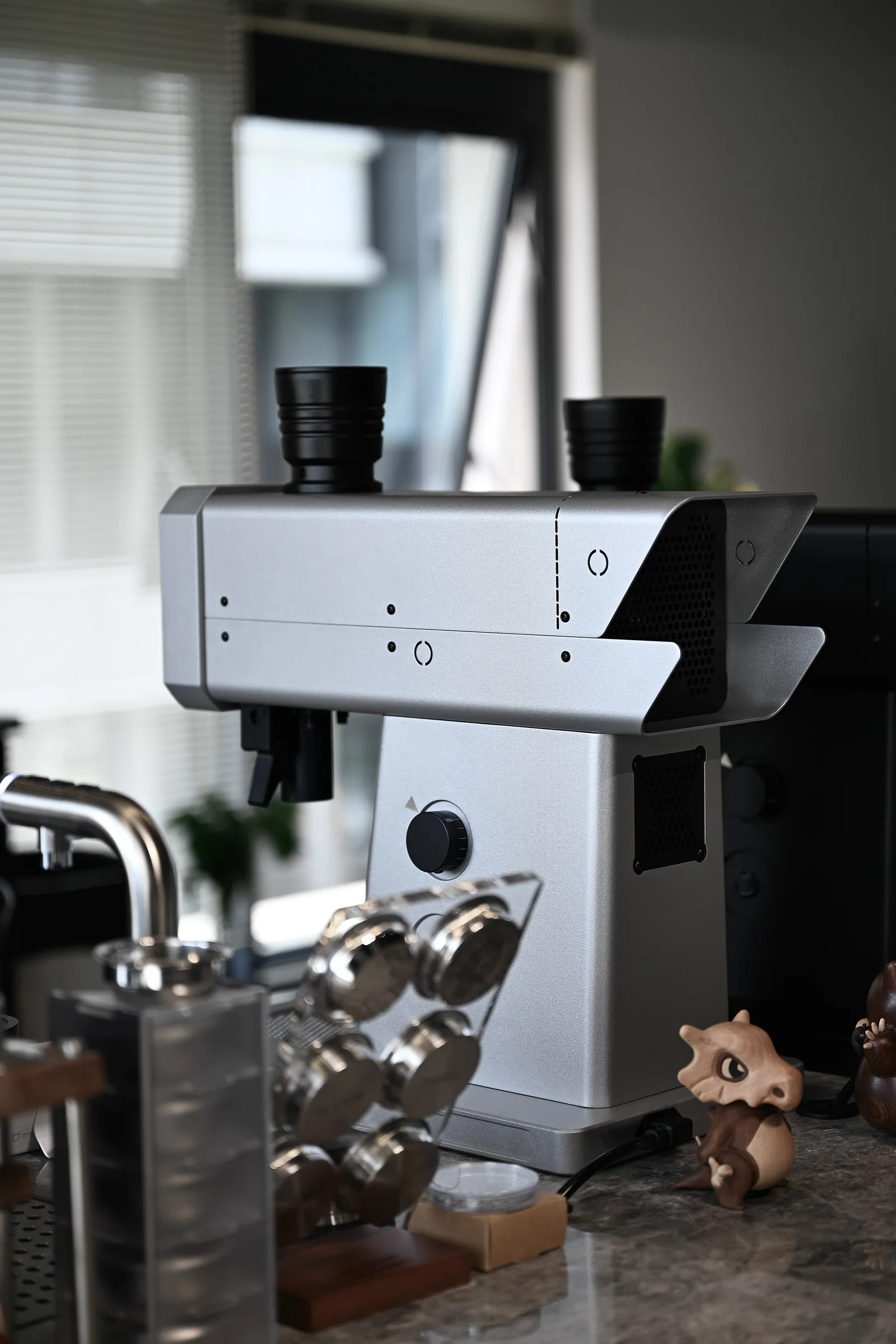 A light-coloured FM grinder among espresso tools on a coffee counter