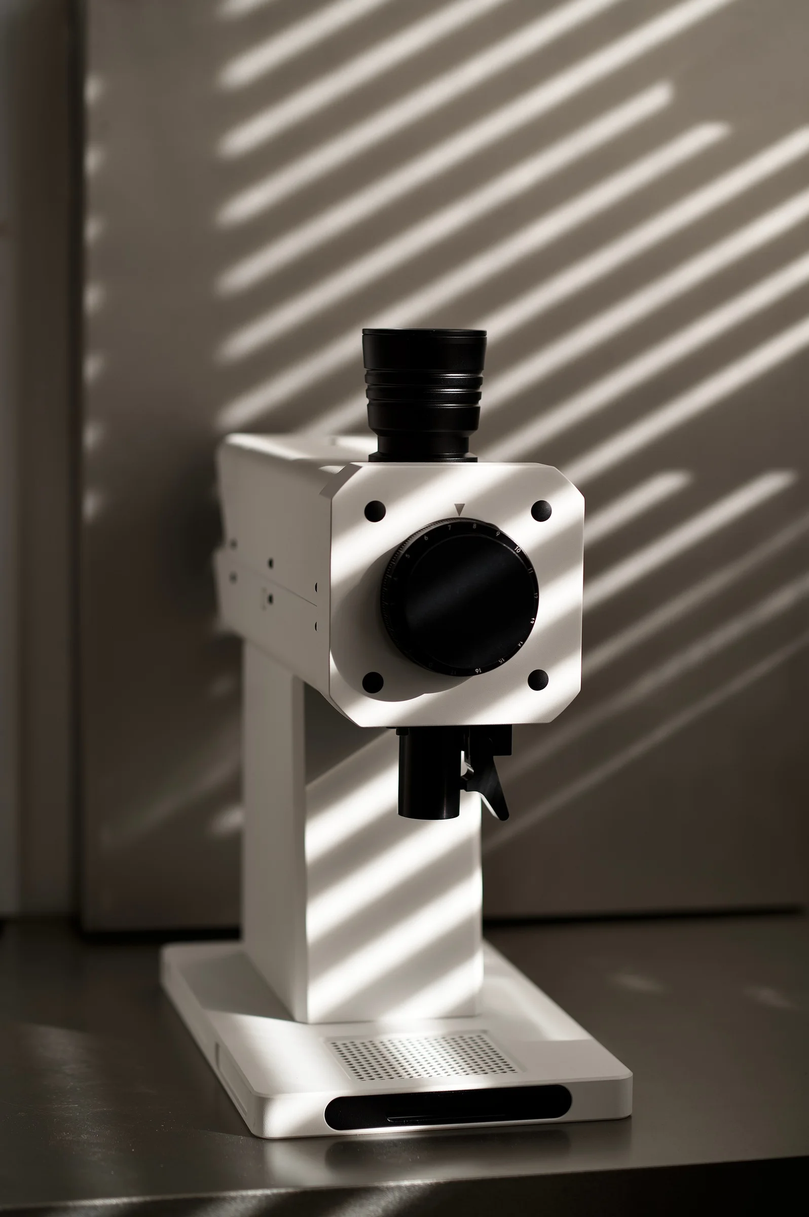 Window-blind shadows falling across a white FM grinder